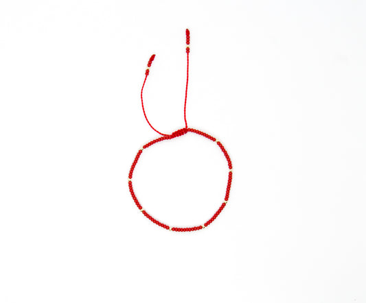 Pulsera roja tejida con puntos de oro