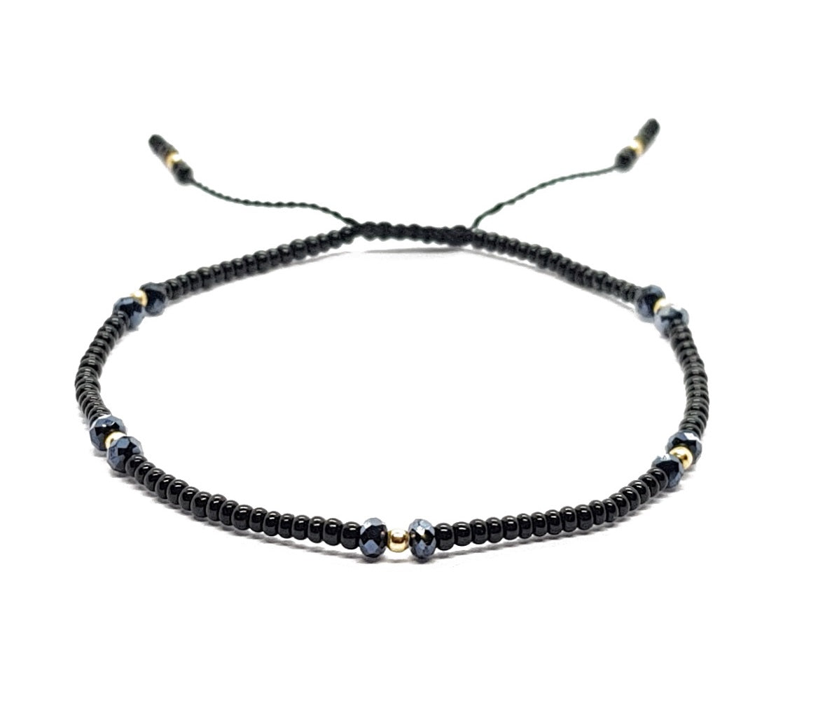Pulsera negra con cristales y puntos de oro